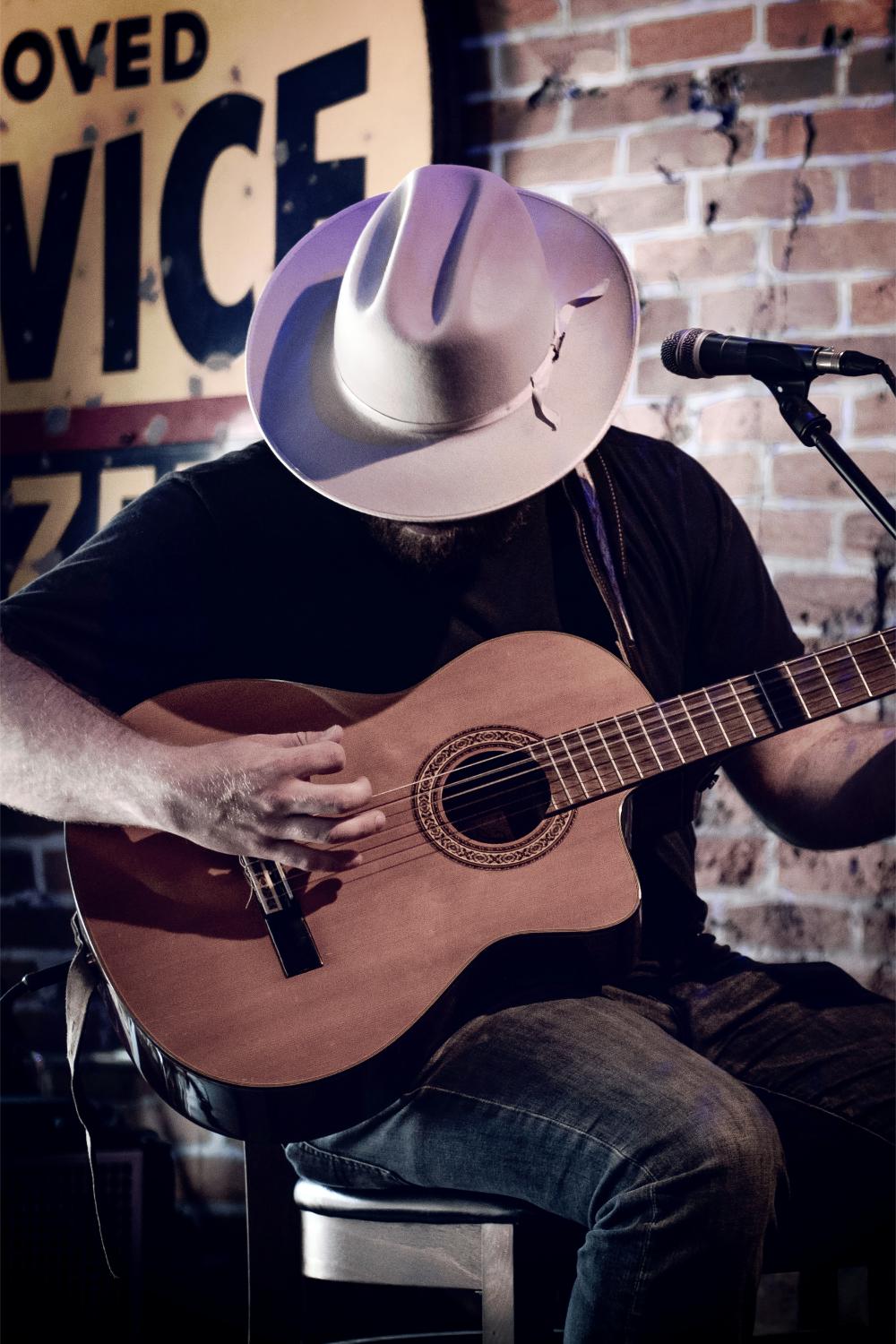 Guitarist with hat playing acoustic guitar